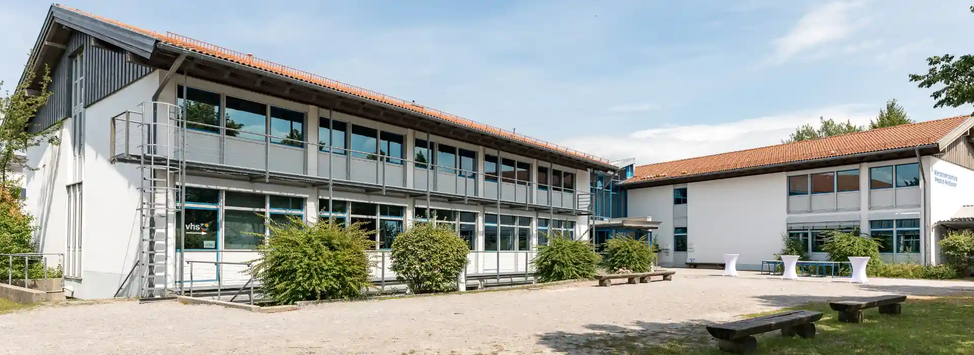 Das Schulgebäude im Sommer mit Pausenhof